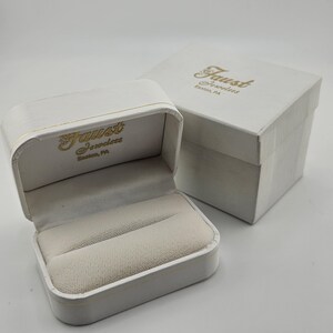 May include: White ring box with a gold inscription that reads "Faust Jewelers Easton, PA".