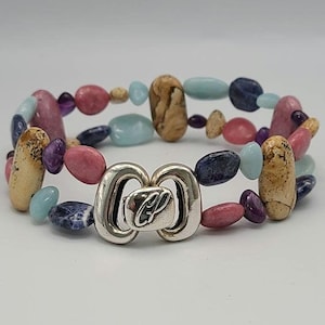 May include: A multi-coloured beaded bracelet with a silver clasp. The beads are various shades of pink, blue, brown, and purple.