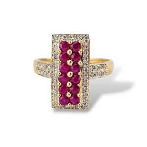 May include: A gold ring featuring a rectangular cluster of vibrant red gemstones, likely rubies, set in a rectangular frame. The frame is surrounded by smaller, clear gemstones, possibly diamonds. The ring's band is also adorned with smaller gemstones.