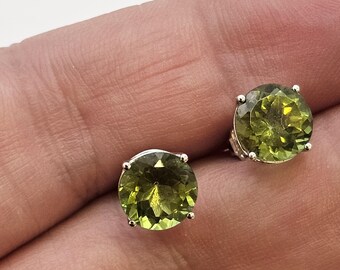 May include: A pair of silver stud earrings with round, green gemstones.