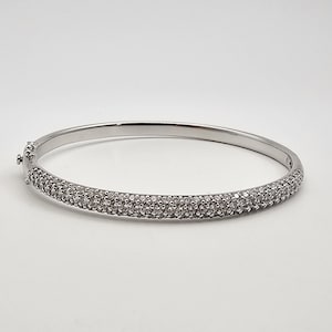 May include: A silver bangle bracelet with a pave setting of small diamonds.