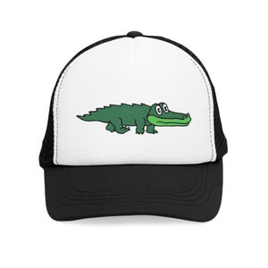 May include: A black and white trucker hat featuring a cartoon alligator in green. The alligator is walking and has a green snout and a white background. The hat has a black brim and mesh backing.