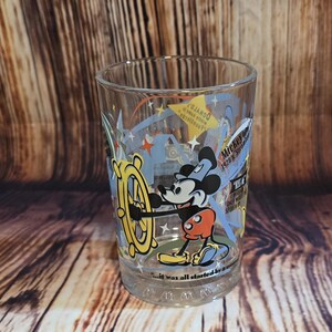 May include: Clear glass tumbler featuring Mickey Mouse at the helm of a ship's wheel. The design includes the text "Mickey 1928's" and "...it was all started by a mouse". The tumbler has a classic cartoon style.