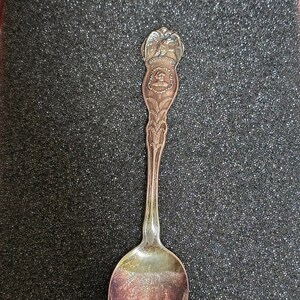 May include: A silver spoon with an ornate handle featuring an eagle design and the inscription "The United States of America".