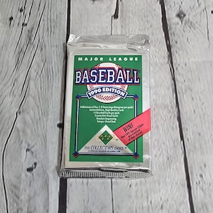 May include: A sealed pack of 1990 Major League Baseball cards. The pack is green and white with a baseball graphic and the text "1990 Edition". The pack also includes a red sticker that says "WIN!" and mentions four 1991 season tickets.