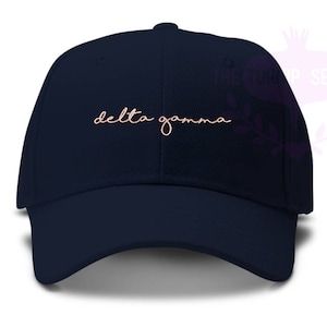May include: A navy blue baseball cap with the text "delta gamma" embroidered in pink on the front.