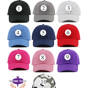 May include: Ten different color toddler hats with numbers 1 through 10 on them. The hats are all the same style, with a curved brim and a white logo on the front.