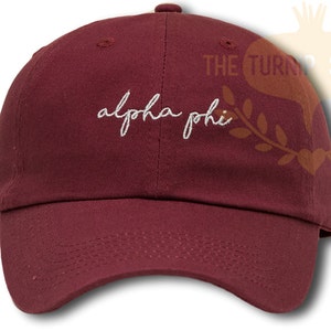 May include: A maroon baseball cap with white embroidered text that reads "alpha phi".