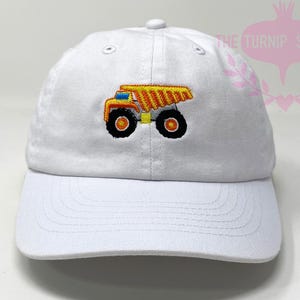 May include: White baseball cap with an embroidered yellow dump truck on the front.
