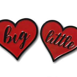 May include: Two red heart-shaped pins with black outlines. The left pin says "big" and the right pin says "little".