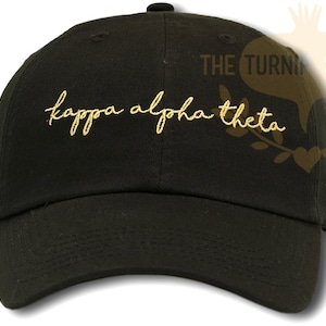May include: A black baseball cap with a gold embroidered inscription that reads "kappa alpha theta".
