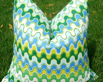 Peut inclure: Un coussin décoratif avec un motif ondulé dans des tons de bleu, vert et jaune. Le coussin est fait d'un tissu blanc doux.