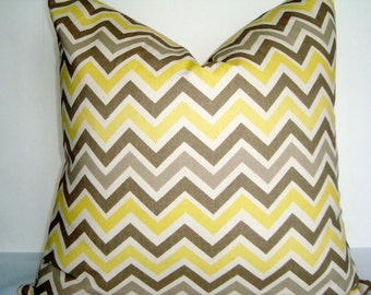 May include: A yellow and brown chevron patterned throw pillow. The pillow is made of a soft, woven fabric.
