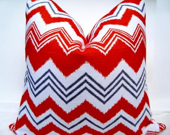 May include: Red, white, and blue chevron patterned throw pillow. The pillow is made of a soft, woven fabric.