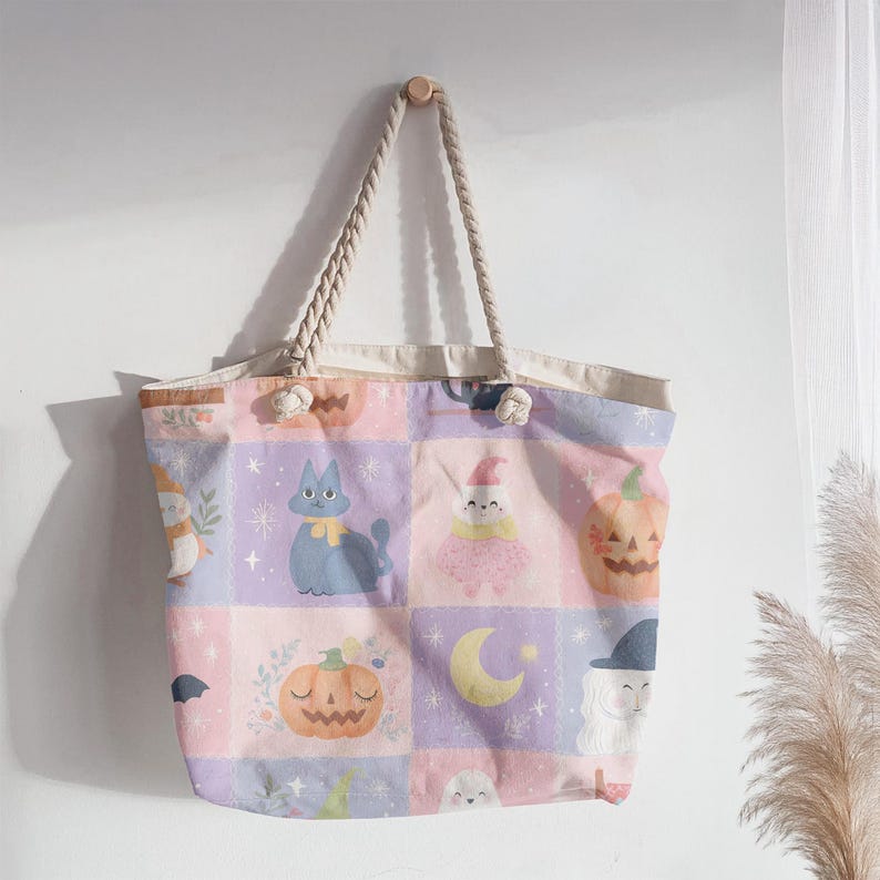 K&ouml;nnte beinhalten: Eine Tragetasche mit einem Gittermuster aus pastellfarbenen rosa und violetten Quadraten. Das Design zeigt Illustrationen einer blauen Katze, eines K&uuml;rbisses, einer Mondsichel, eines Geistes und eines Hexenhutes. Die Tasche hat zwei dicke Kordelhenkel.