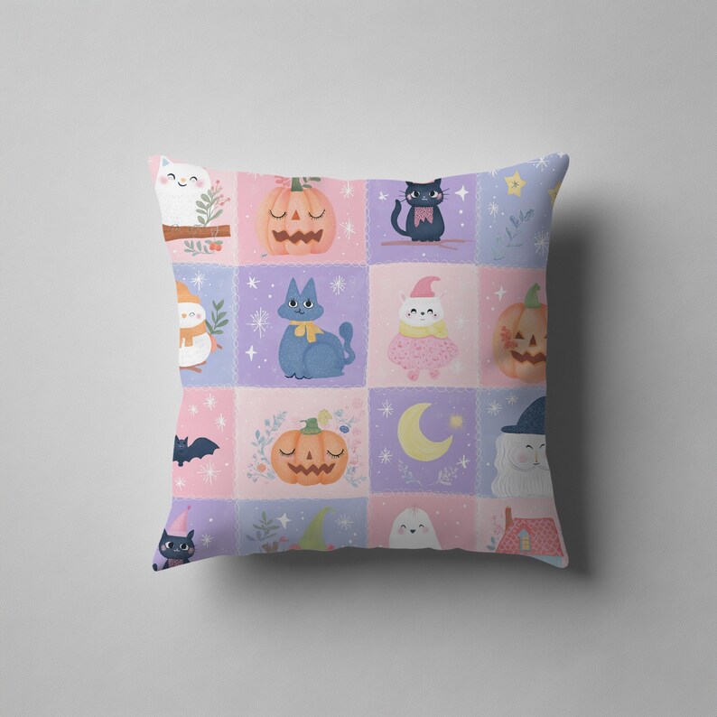 K&ouml;nnte beinhalten: Ein quadratisches Dekokissen mit einem Gittermuster aus pastellrosa und hellvioletten Quadraten. Das Design zeigt Illustrationen von Katzen, K&uuml;rbissen, Geistern, Flederm&auml;usen, Sternen und einer Mondsichel in einem weichen, cartoonartigen Stil.