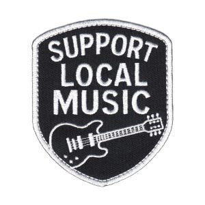 Puede incluir: Un parche bordado en forma de escudo con fondo negro y borde blanco. El texto SUPPORT LOCAL MUSIC está bordado en letras mayúsculas blancas sobre un contorno blanco de una guitarra eléctrica centrado en la parte inferior del parche.