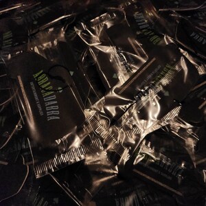 May include: A pile of black and green car air fresheners with the text "Abracadabra Entertainment & Supplies" on them.