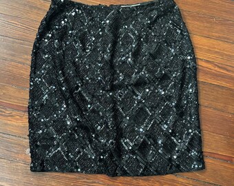 May include: A black sequined skirt with a diamond pattern. The skirt is knee-length and has a fitted silhouette.