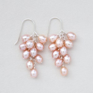 This beautiful pair of dangle earrings features high-luster Freshwater pink pearl oval drops. They are gradually hand-wrapped from top to bottom with sterling silver head pins and finished with sterling silver ear hooks.