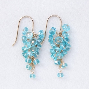 May include: A pair of dangle earrings with a cluster of light blue gemstone beads hanging from gold-toned hoops.