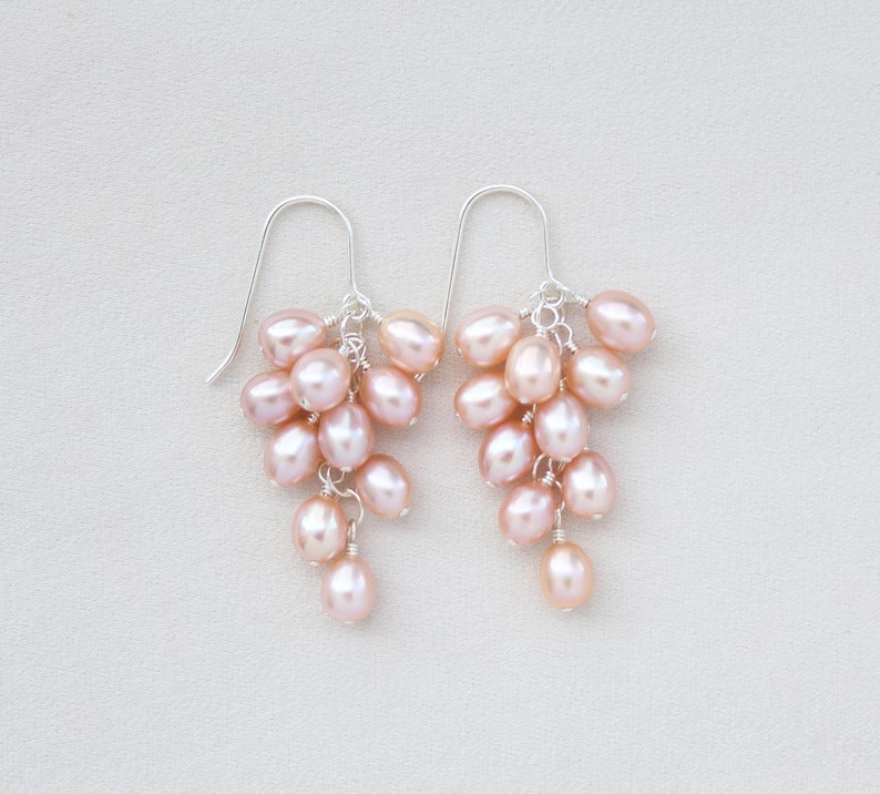 This beautiful pair of dangle earrings features high-luster Freshwater pink pearl oval drops. They are gradually hand-wrapped from top to bottom with sterling silver head pins and finished with sterling silver ear hooks.
