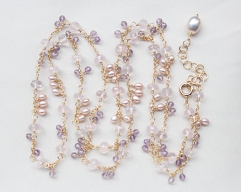 Könnte beinhalten: Eine lange goldene Kette mit einer filigranen Anordnung aus kleinen, facettierten violetten Amethystperlen, blassrosa Rosenquarzsteinen und glatten, ovalen weißen Perlen. Die Halskette verfügt über einen runden Verschluss und eine Kette.