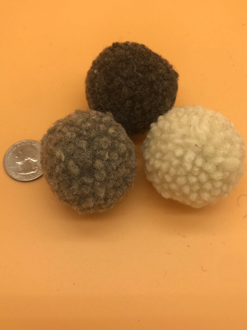 Bouncy Felted Wool Cat Balls. This image shows 3 small wool balls. Displayed next to a quarter, showing the balls are about twice the size of a quarter - Great to carry and bat all over the house - Washable plastic free toys with textures cats love