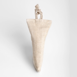 May include: A beige fabric doorstop with a conical shape and a looped rope handle. The doorstop is made of a textured, woven material and is designed to prevent doors from closing. The rope handle is knotted at the top.