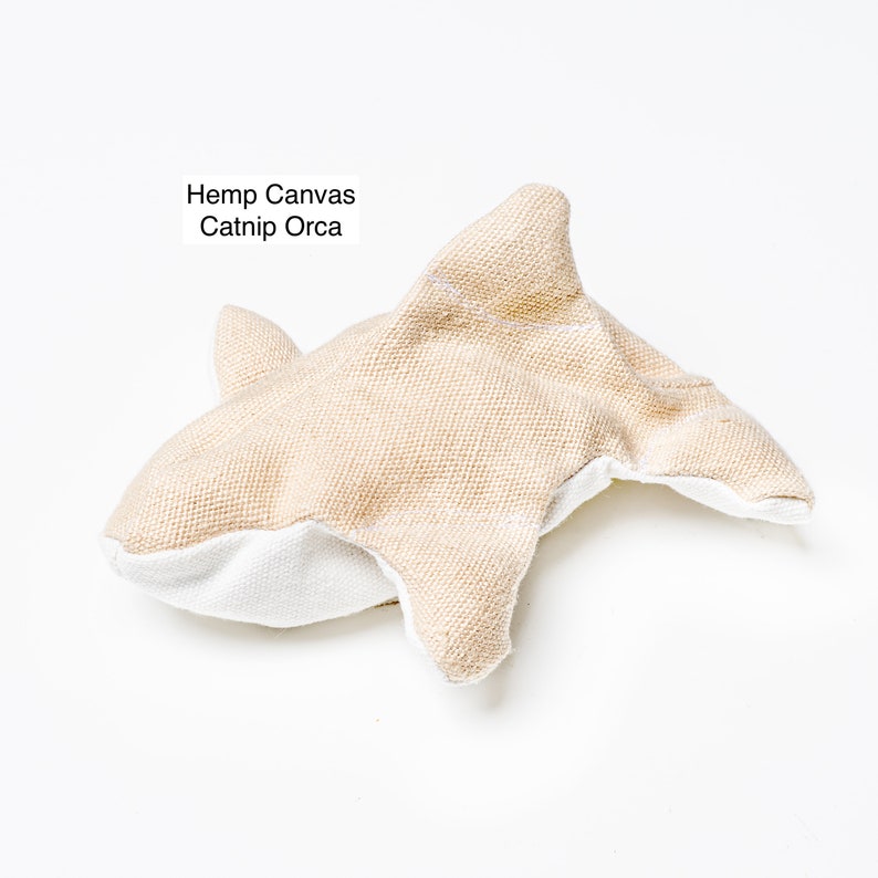 Image shows a single Organic Catnip Orca cat toy.  It is light golden brown in color.  It has 2 side fins, 1 top dorsal fin, and a wide flipper tail.  The background is light grey.  Text in upper left of image says, Hemp Canvas Catnip Orca.