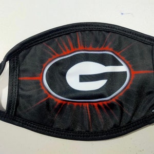 May include: Black face mask with a white 'G' in a red circle with a red starburst design.