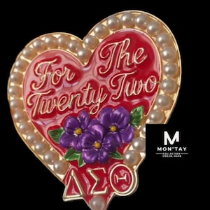 May include: A heart-shaped brooch with a red enamel center, featuring the text "For Twenty Two" in gold script. The brooch is adorned with faux pearls and purple flower accents. The bottom has the Greek letters ΔΣΘ.
