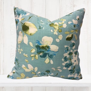 Könnte beinhalten: Ein blaues Kissen mit einem floralen Muster in Weiß-, Grün- und Blautönen.