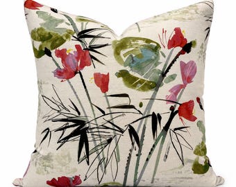 Op de afbeelding: Een vierkant sierkussen met een crèmekleurige stoffen basis en een aquarelprint van rode bloemen, groene bladeren en zwarte bamboestengels. Het ontwerp maakt gebruik van penseelstreekachtige texturen om de botanische elementen weer te geven.