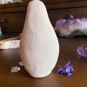 May include: A white ceramic figurine shaped like a pear with a smooth, textured surface.