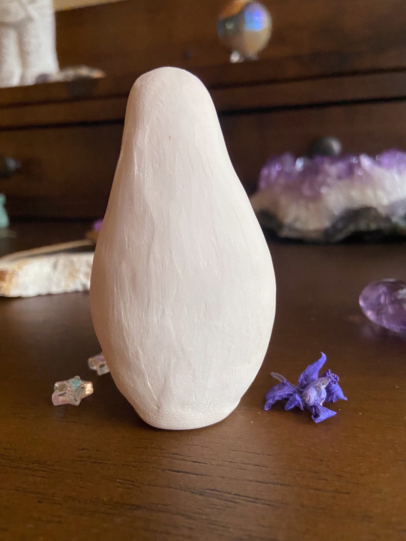 May include: A white ceramic figurine shaped like a pear with a smooth, textured surface.