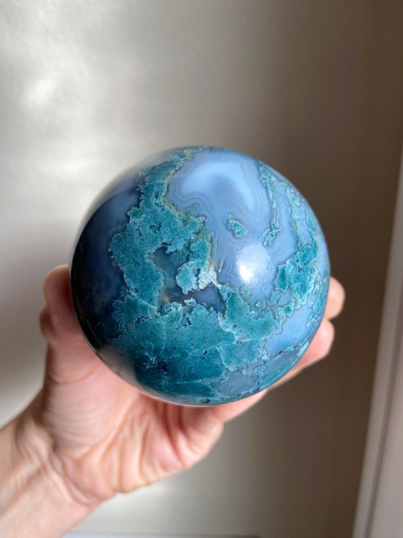 Pu&ograve; includere: Una sfera lucidata in agata muschiata, che mostra una miscela di tonalit&agrave; blu e verde acqua. La superficie della gemma presenta motivi intricati, creando un oggetto decorativo unico. Questa sfera di pietra naturale &egrave; una bella aggiunta a qualsiasi collezione.