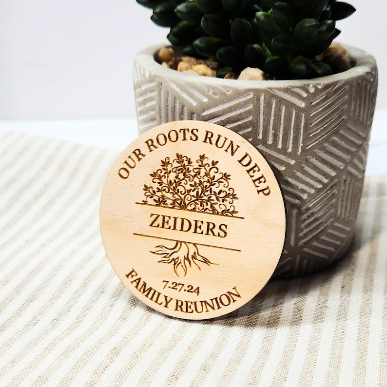 May include: A wooden round sign with the text "Our Roots Run Deep" and a stylized tree with roots. The text "Zeiders Family Reunion 7-27-24" is also on the sign.