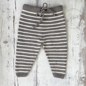 Peut inclure: Pantalon bébé en tricot rayé marron et blanc avec un cordon de serrage à la taille.