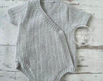 May include: A gray knitted baby onesie with short sleeves and a wrap-around front closure. The onesie has a ribbed texture and a button closure at the neck.