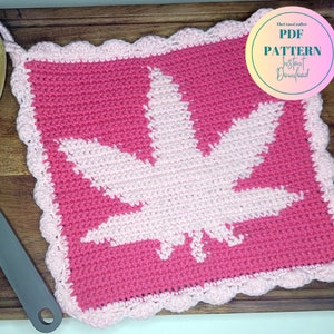 May include: A handmade crochet potholder featuring a cannabis leaf design. The potholder is primarily pink with a lighter pink leaf and a scalloped edge. The text "PDF PATTERN Instant Download" is in a circle in the upper right corner.