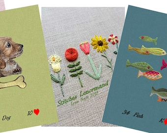May include: Four embroidered cards with different designs. The first card is green and features a brown and white dog with a bone. The second card is beige and features a row of embroidered flowers. The third card is blue and features a school of colorful fish. The fourth card is green and features a cluster of purple flowers.