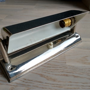 May include: A chrome-plated wall light fixture with a white interior and a light bulb socket. The fixture has a switch on the side and a mounting bracket on the back.