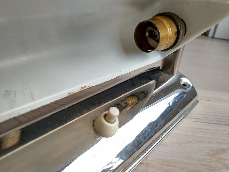 May include: A white and chrome wall light fixture with a brass light bulb socket and a white toggle switch.