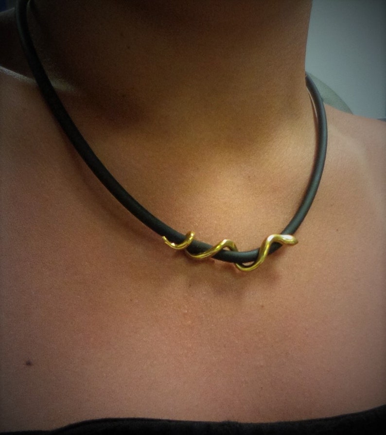 May include: A black choker necklace with a gold snake-shaped pendant.
