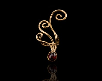 May include: Gold ear cuff with a red gemstone and a swirling design.
