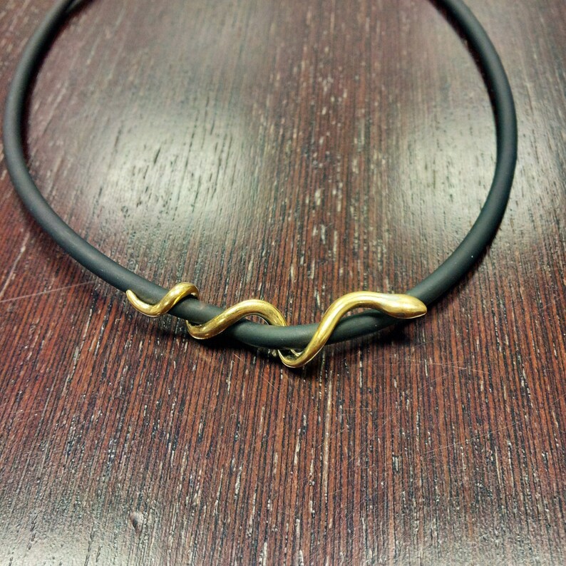 May include: A black rubber choker necklace with a gold snake charm.