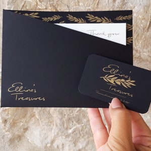 May include: Black envelope with gold leaf design and the text "Ellina's Treasures" on the front. A white card with the text "Thank you" is inside the envelope. A black gift card with gold leaf design and the text "Ellina's Treasures" is on top of the envelope.