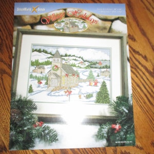 May include: A cross-stitch pattern for a winter village scene with a church, houses, and snow-covered trees. The pattern is titled "Village Holidays" and is from StitchWorld.