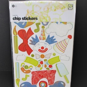 May include: A set of colorful chip stickers featuring a clown with a red nose, a bow tie, and a party hat. The stickers are on a white background with the text "cupcake chip stickers" and a logo for "BasicGrey".